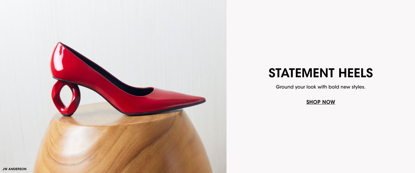 1 photo, of a single shiny red high heel shoe with an oval shaped heel, on top of a circular wooden side table in front of a white background.