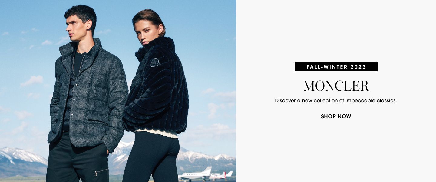 1 photo, of a male and female model standing outside, snow capped mountain peaks behind them, the male model in a Moncler dark blue puffer like coat and black pants, the female model in a Moncler black faux fur jacket and black leggings.