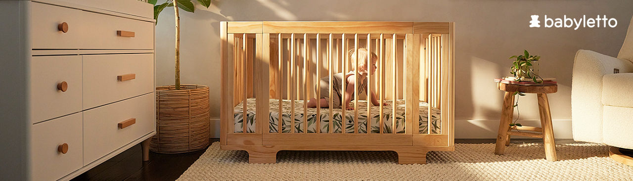 1 photo of baby in wooden Babyletto crib, in nursery with beige rug, beige dresser, and beige plush chair.