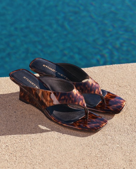 A pair of Stuart Weitzman tortoiseshell print thong sandals. Shop thong sandals.