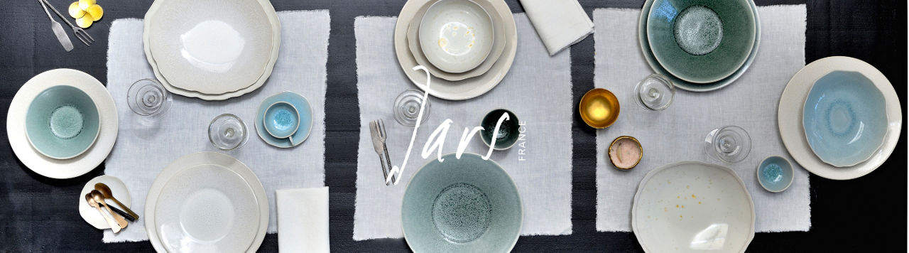 1 photo, an overhead view of a set table with Jars dinnerware place settings in muted tones of gray, green, and blue.