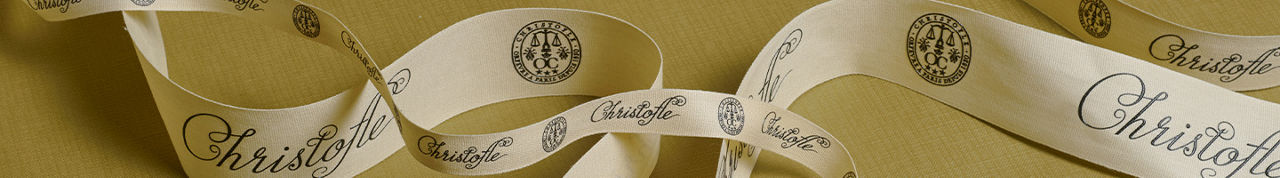 1 photo, of a winding cream color ribbon printed with the Christofle logo, repeated across the ribbon.