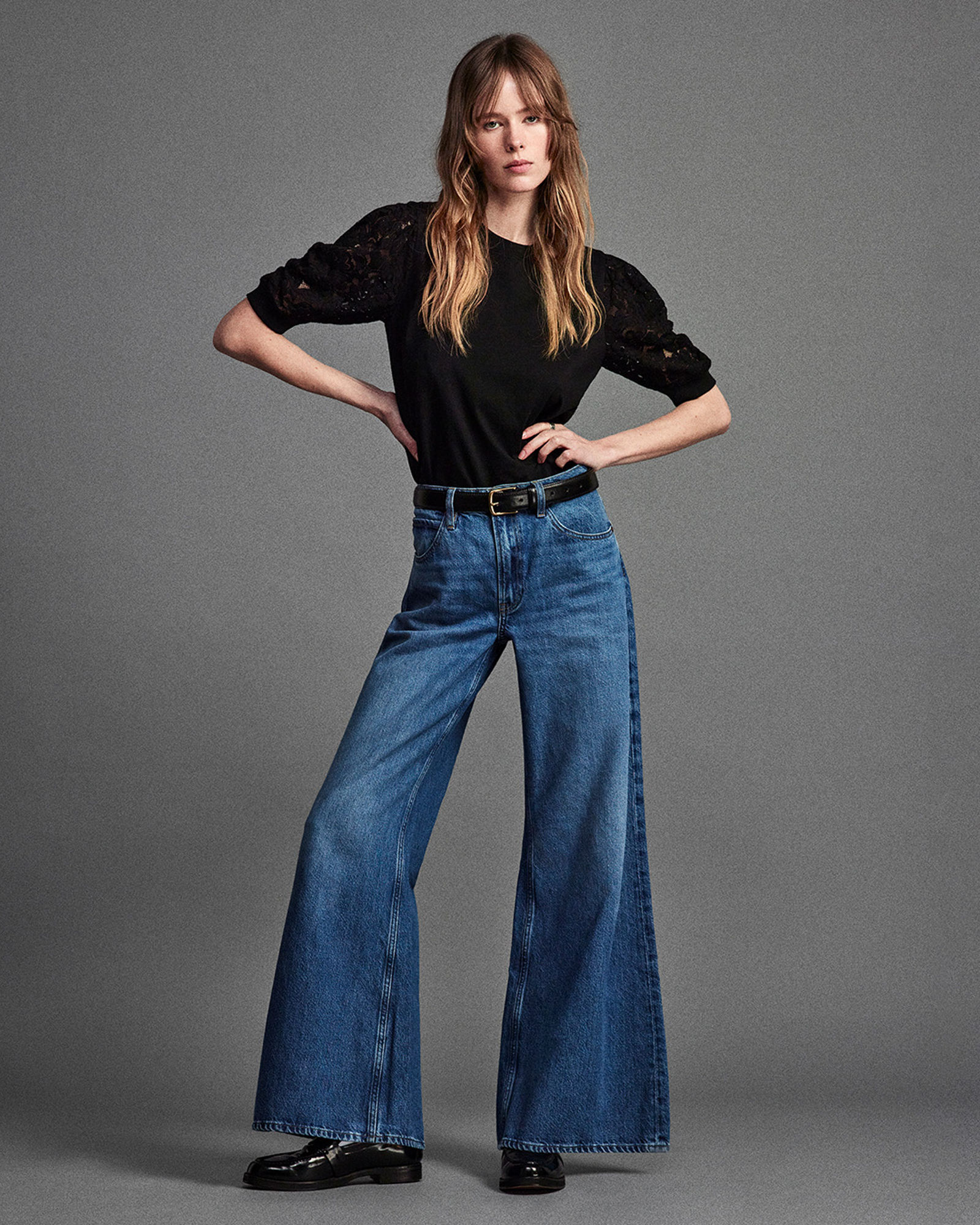 1 photo of female model in black shirt and Frame bell bottom jeans, in blue denim.