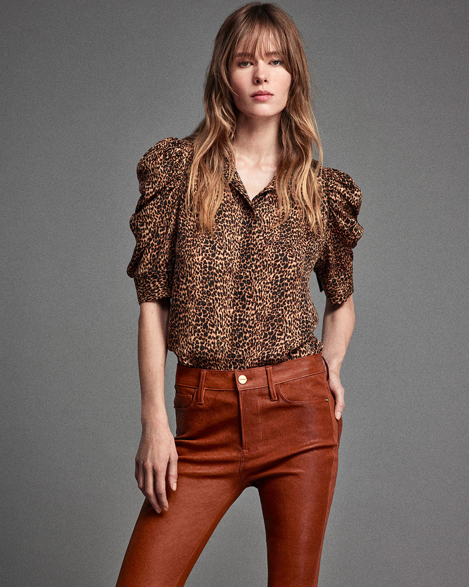 1 photo of female model in brown and black Frame puff sleeve blouse and dark brown fitted jeans.