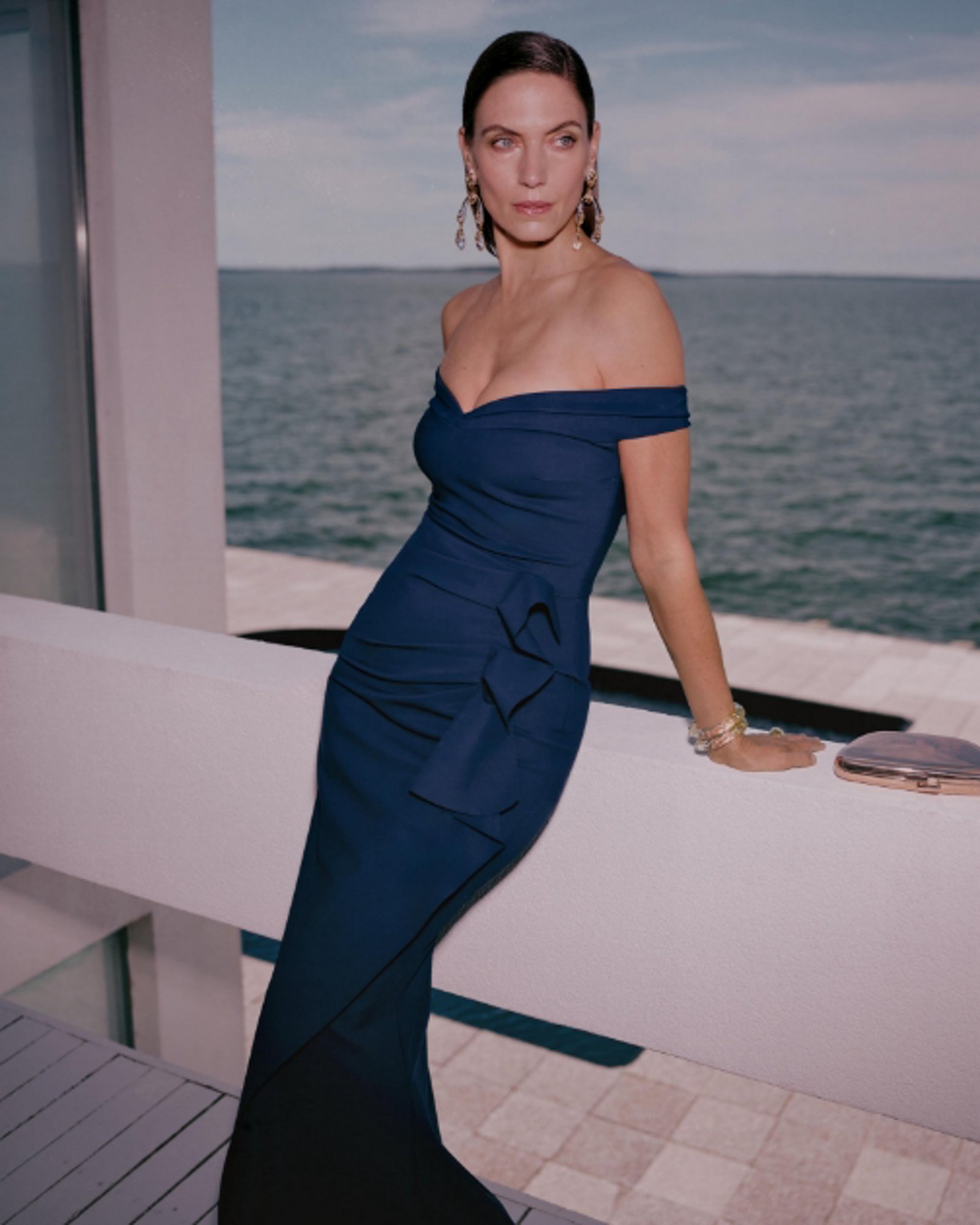 1 photo of female model in dark teal over the shoulder fitted gown.