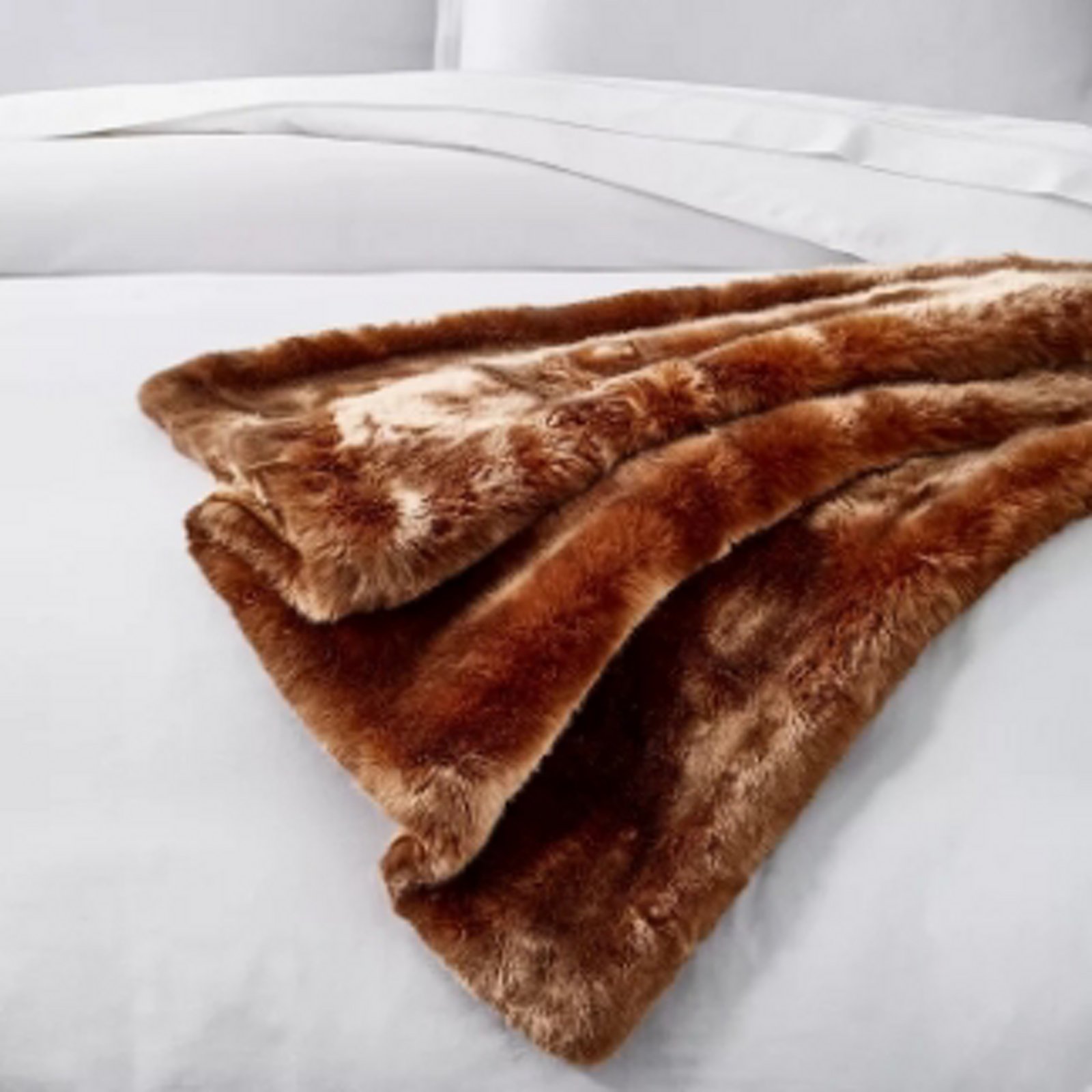 1 photo of brown Hudson Park faux fur throw, on top of bed with white Hudson Park sheets and pillows.