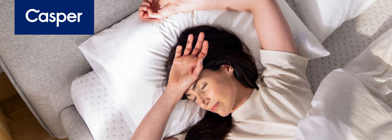 1 photo of female model in white tee shirt sleeping on a Casper mattress with white pillow and white bed sheets and white comforter.