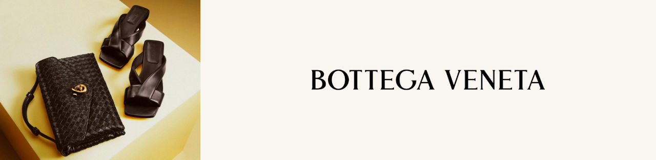 Bottega Veneta. A black quilted Bottega Veneta clutch next to a pair of black high heel sandals with wide straps.