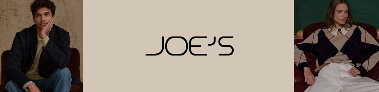 Joes. A man in Joes Jeans black jacket, beige sweater, and blue jeans, a woman in a brown and black argyle sweater and chinos.