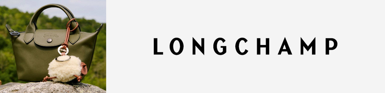 Longchamp. A dark green Longchamp bag with a shearling sheep bag charm on top of a rock.
