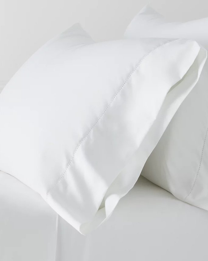 White pillows atop a bed with white sheets.