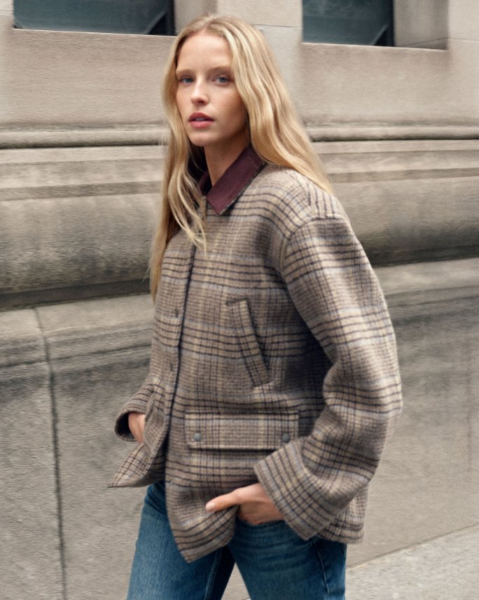 1 female model in gray tweed barn jacket and blue jeans.
