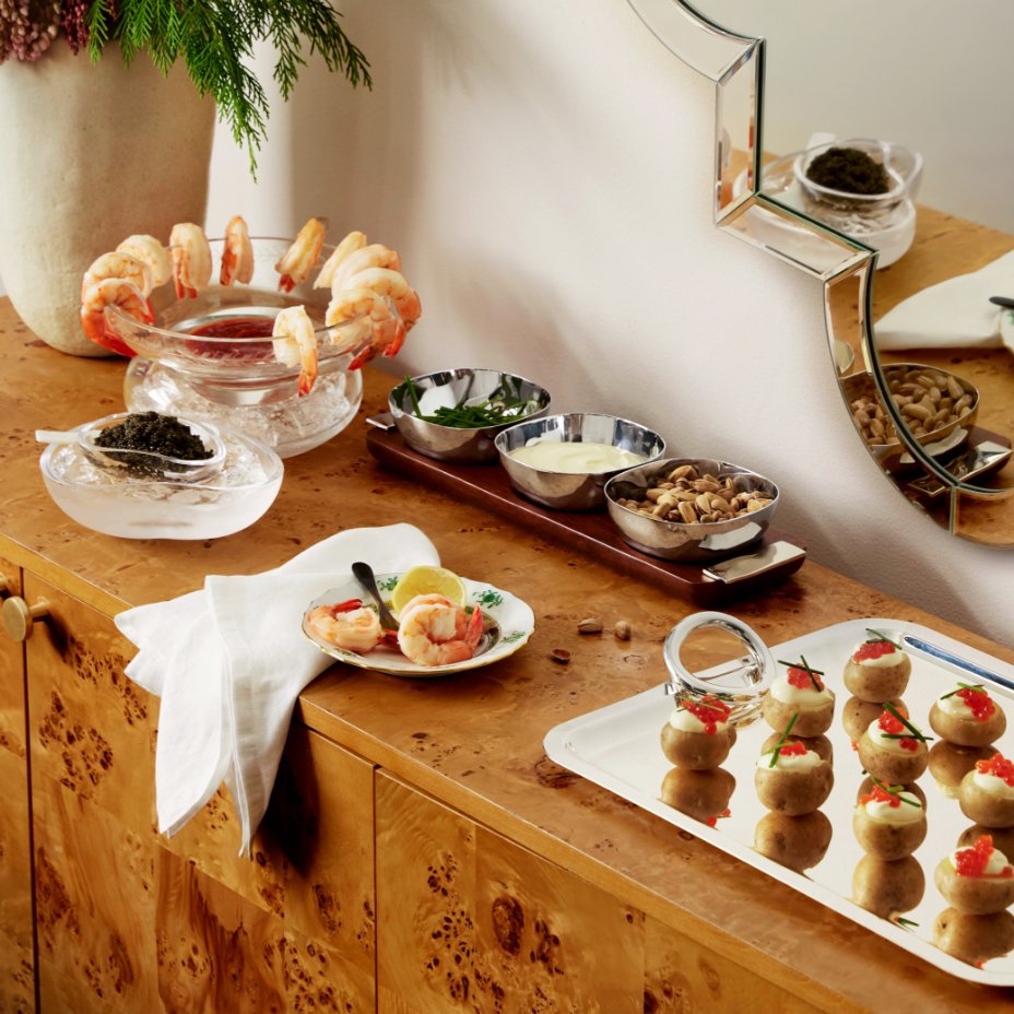 A sideboard filled with appetizers and canapes on silver trays and bowls.