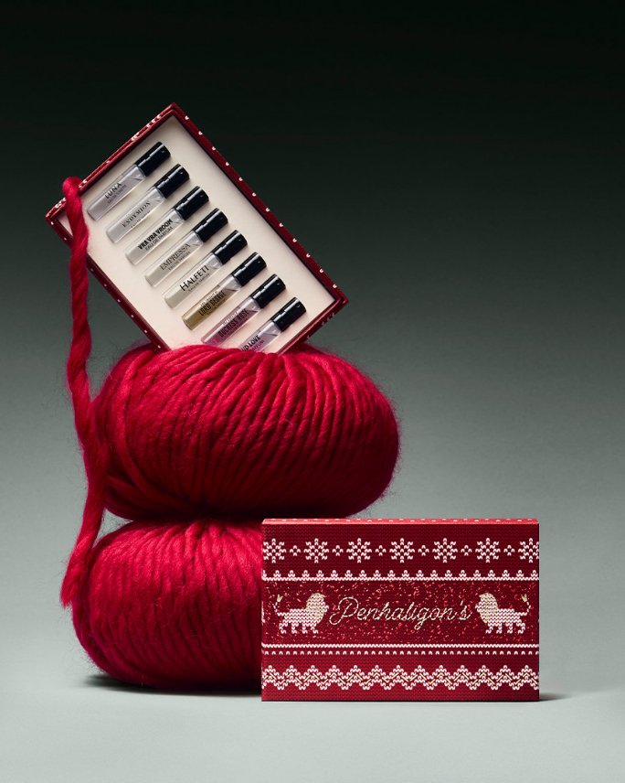 A box of Penhaligons sampler fragrances nestled in a skein of red yarn.