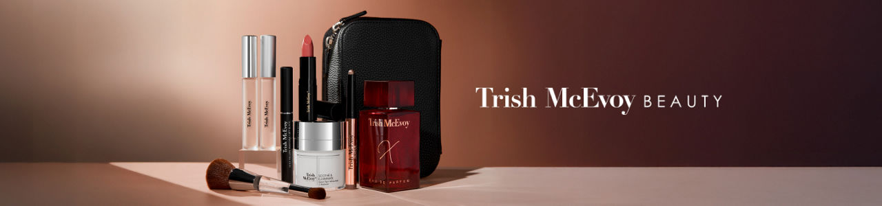 1 photo, of various Trish McEvoy beauty and skincare products, including a makeup brush, lipstick, and eau de parfum, arranged in front of a black makeup bag.