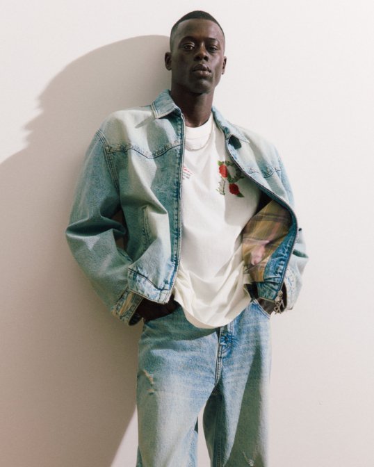 Male model in white tee shirt and light blue denim jacket and pants.