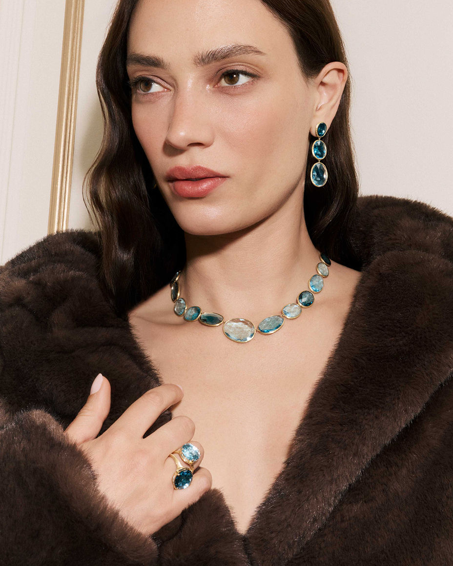 A woman in Marco Bicego blue stone drop earrings, necklace and rings. Exceptional fine jewelry, Marco Bicego.