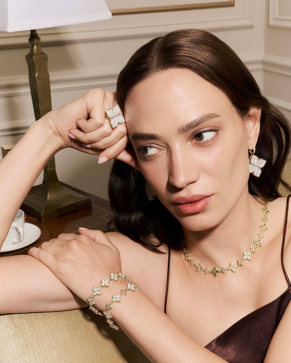 A woman in Roberto Coin flower gold and diamond earrings, necklace & bracelets. Exceptional fine jewelry, Roberto Coin.