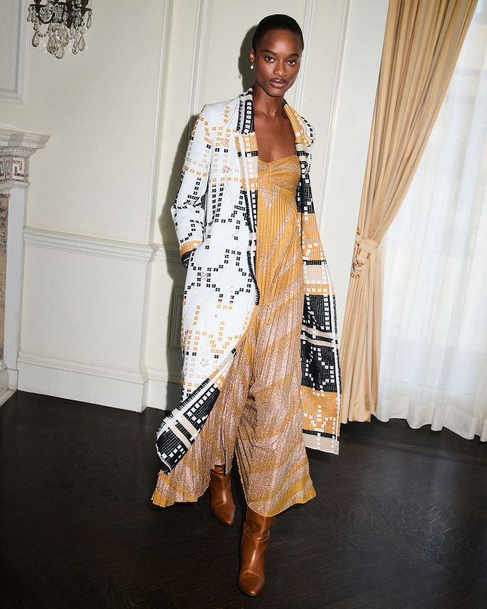 A woman in a yellow & gray metallic print Forte Forte dress & pixelated long coat. The fall collections, Forte Forte.