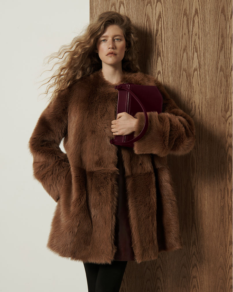 A woman in an oversized brown shearling coat. Shop shearling jackets.