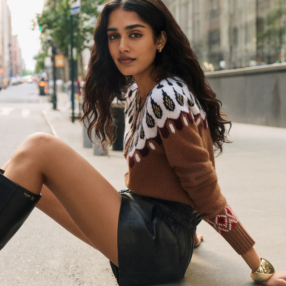 A woman sitting on the sidewalk in a brown print cashmere sweater & shorts. The Cashmere Guide, Aqua Cashmere.