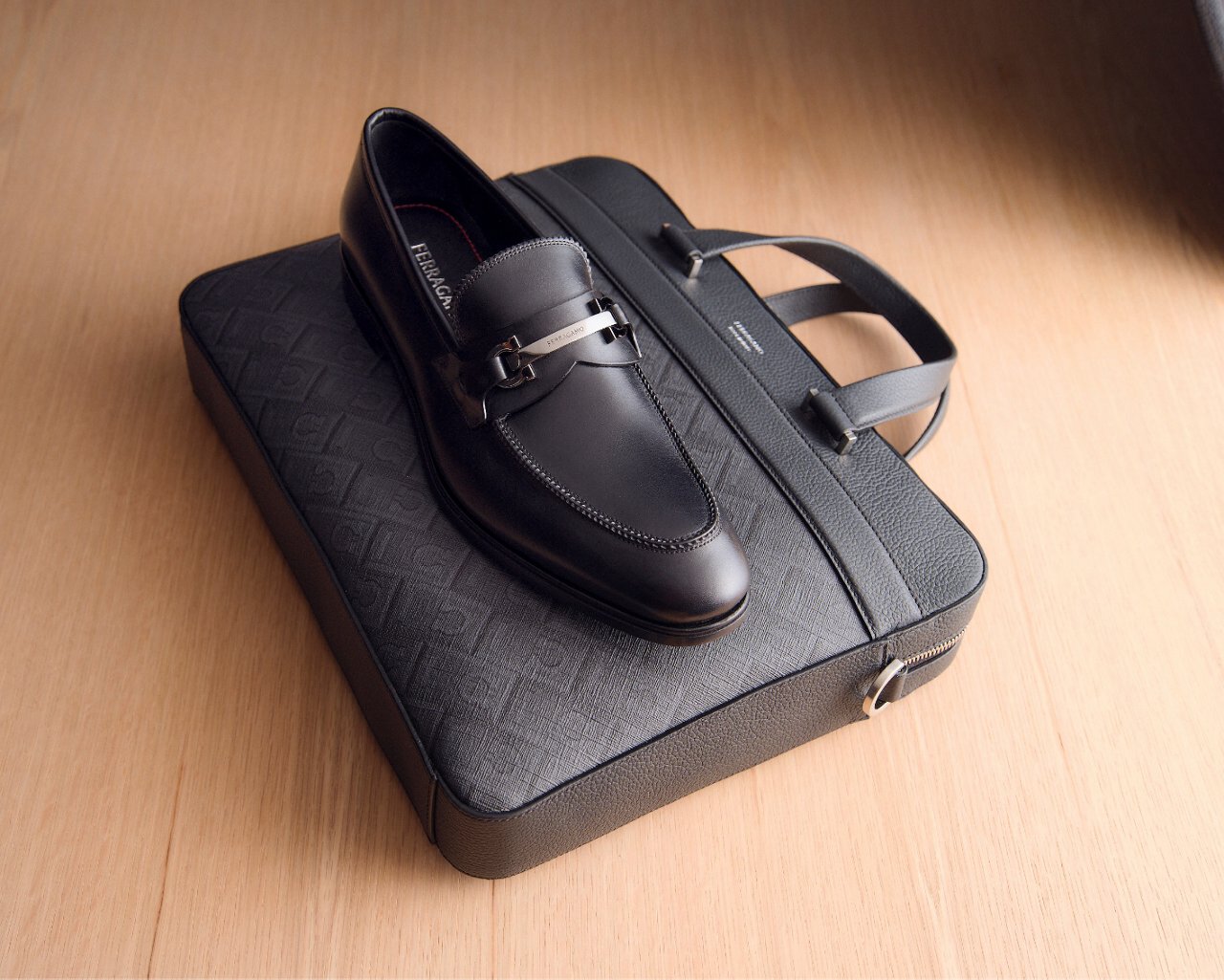 A black loafer on top of a black briefcase. All new for spring. Shop mens new arrivals.