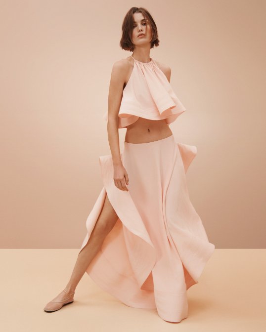 Woman in a light pink Stella McCartney flowy halter top and matching maxi skirt.