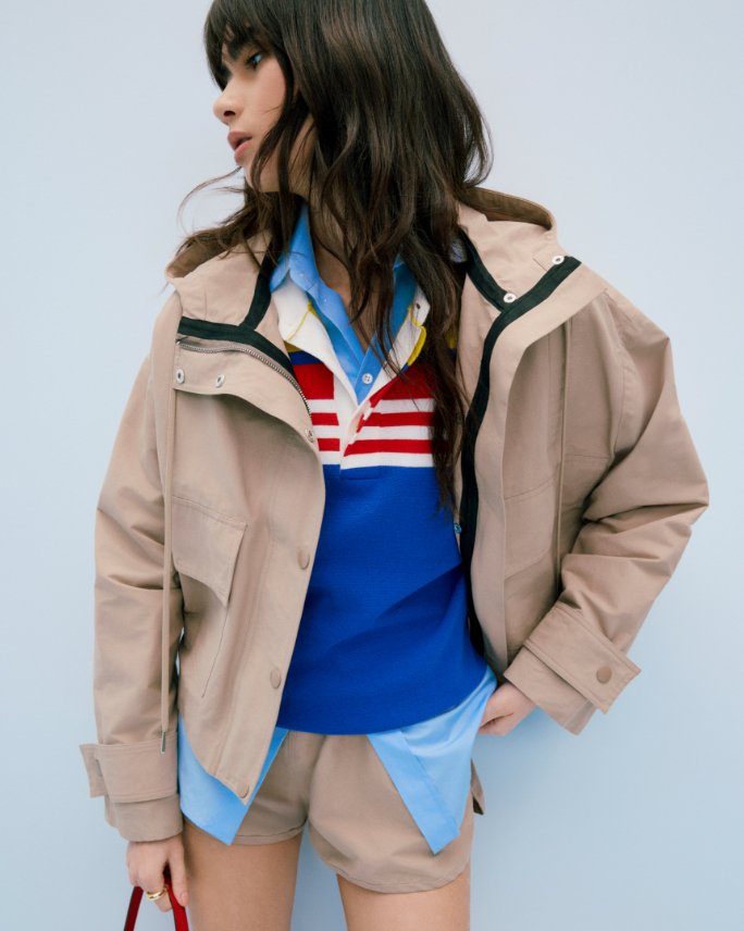 A woman in a tan jacket over 2 layers of rugby shirts. Shop spring jackets.