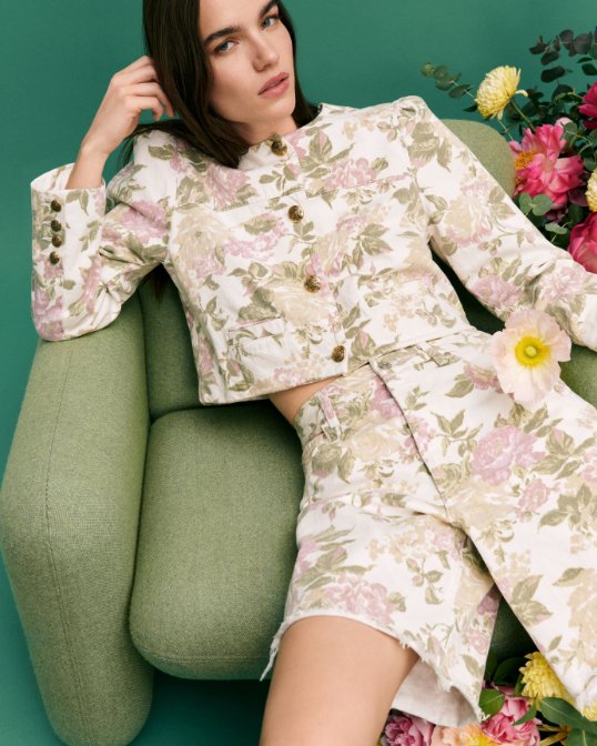 A woman sitting in a pink & green long sleeve floral top and matching shorts. Shop allover florals.