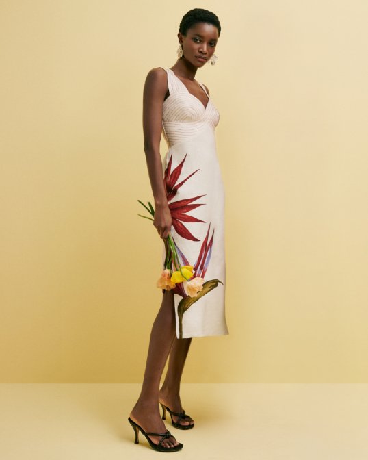 A woman in a sleeveless ivory midi dress with a large orchid print. Shop single statement blooms.
