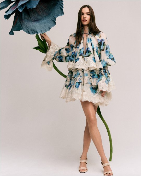 A woman in a frilly, bohemian style white & blue floral print top & matching mini skirt. Shop feminine details.