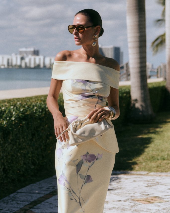 Woman in a yellow off shoulder dress with delicate purple flowers. Shop featured shops, well dressed guest guide.