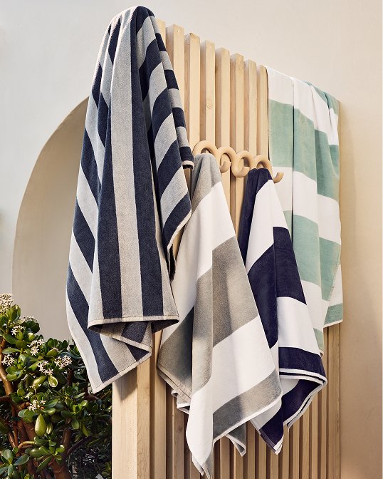 Striped beach towels hanging on a fence.