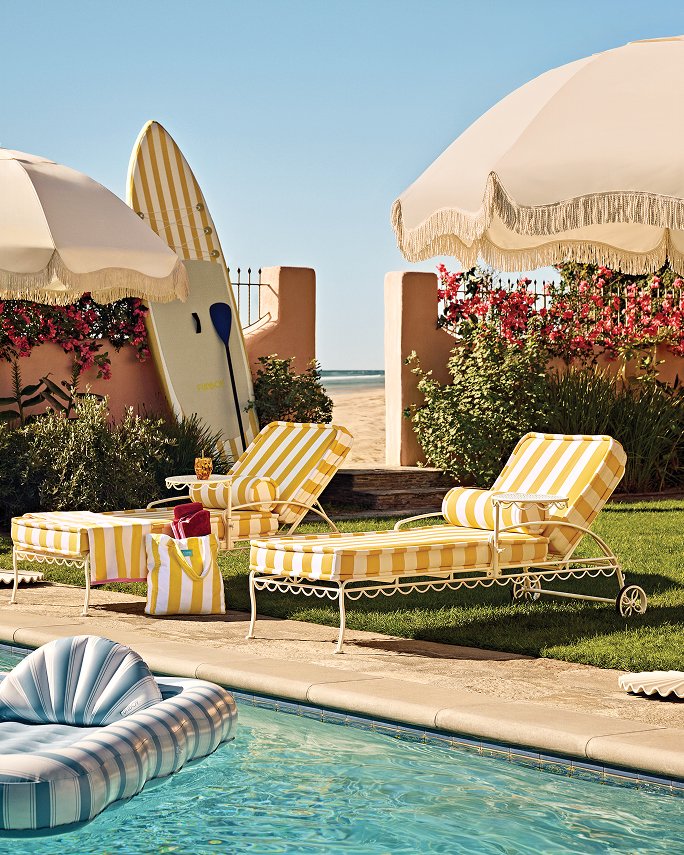 Yellow & white striped loungers & a beach umbrella next to a pool. Beach bound, outdoor essentials.
