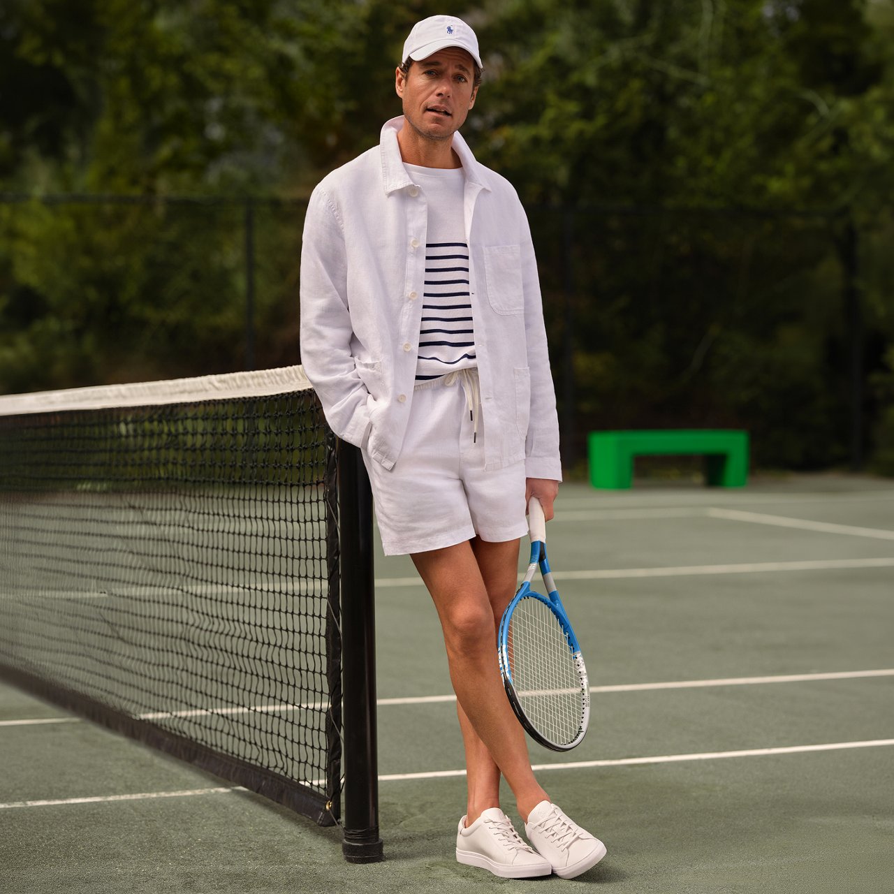 A man in an all white Polo Ralph Lauren tennis outfit on a tennis court.