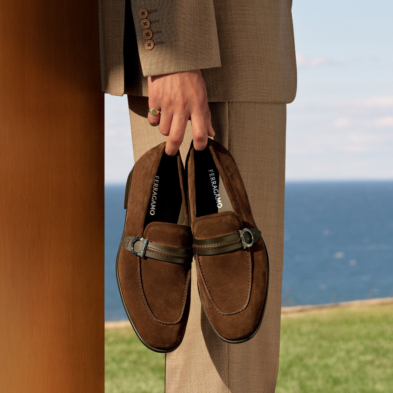 A mans hand holding a pair of brown suede loafers. Top fathers day gifts, loafers.
