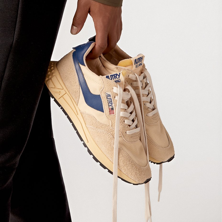 A hand holding a pair of off white Autry sneakers. Lookbooks & guides, the sneakers guide.