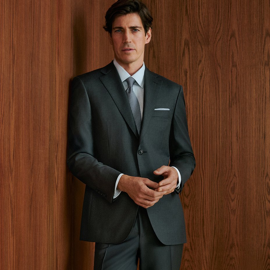 A man in a dark suit over a light blue shirt. Explore the guides, mens suits.