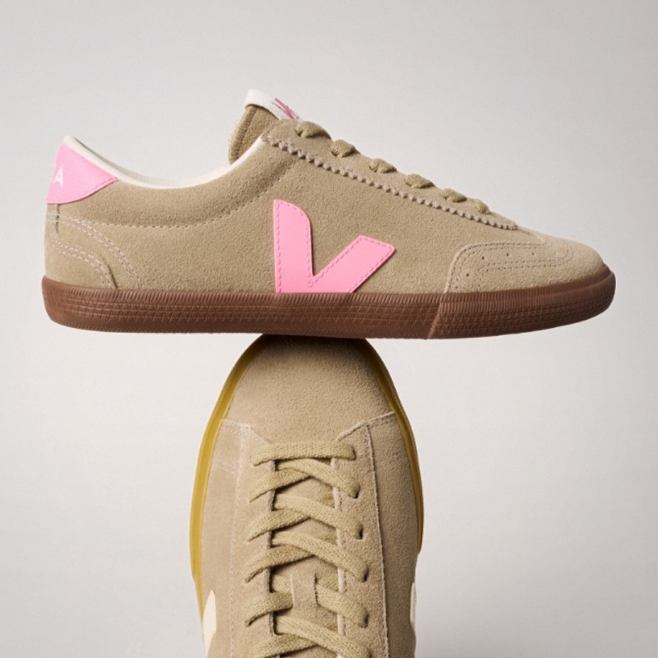 A pair of Veja tan sneakers balancing atop each other. Explore the guides, sneakers.