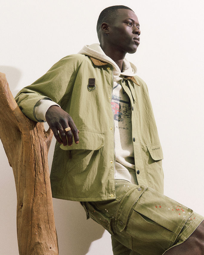 A man in a casual light green jacket over a hoodie & matching cargo shorts. Featured shops, the weekend shop.