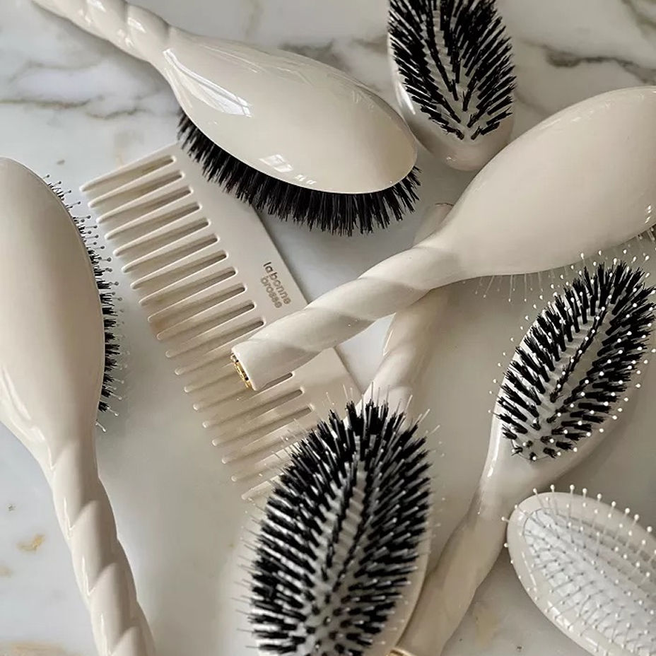 A pile of white hairbrushes and a comb. Summer beauty, hair care.
