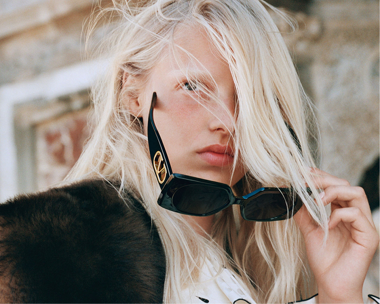 A woman pulling off her Valentino Garavani sunglasses. Statement eyewear, Valentino Garavani.