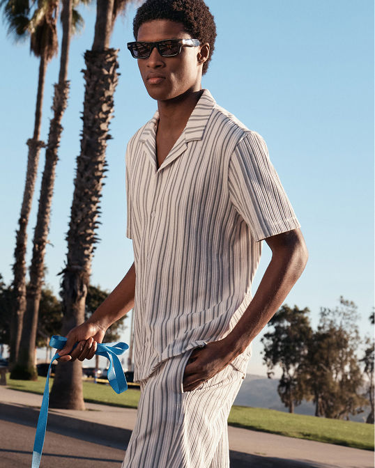 A man in a matching striped short sleeve top and shorts. Shop mens shirts.