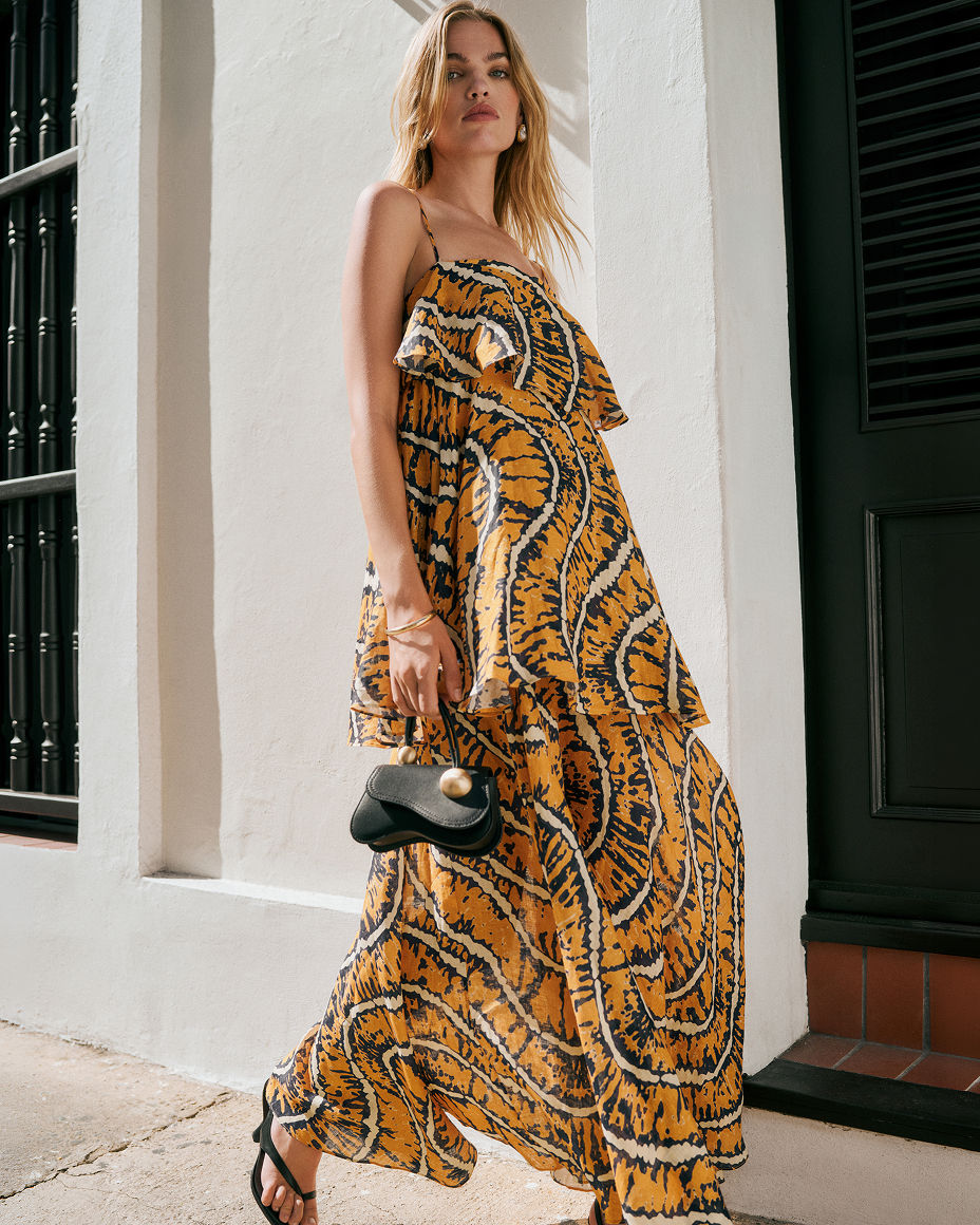A woman in an orange & black printed, tiered, sleeveless maxi dress. Summers most wanted, dresses.