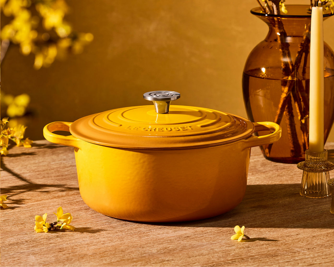 A yellow Le Creuset Dutch oven on a counter bathed in golden light. New home arrivals. Shop Le Creuset.