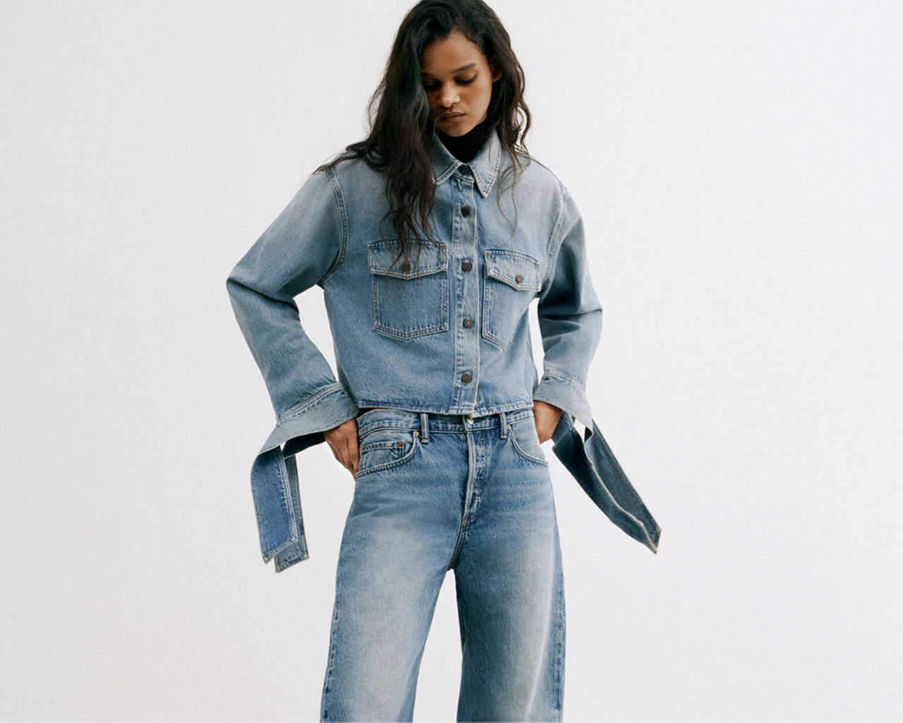 A woman in blue jeans & buttoned up jean jacket with oversized sleeves. The denim guide.