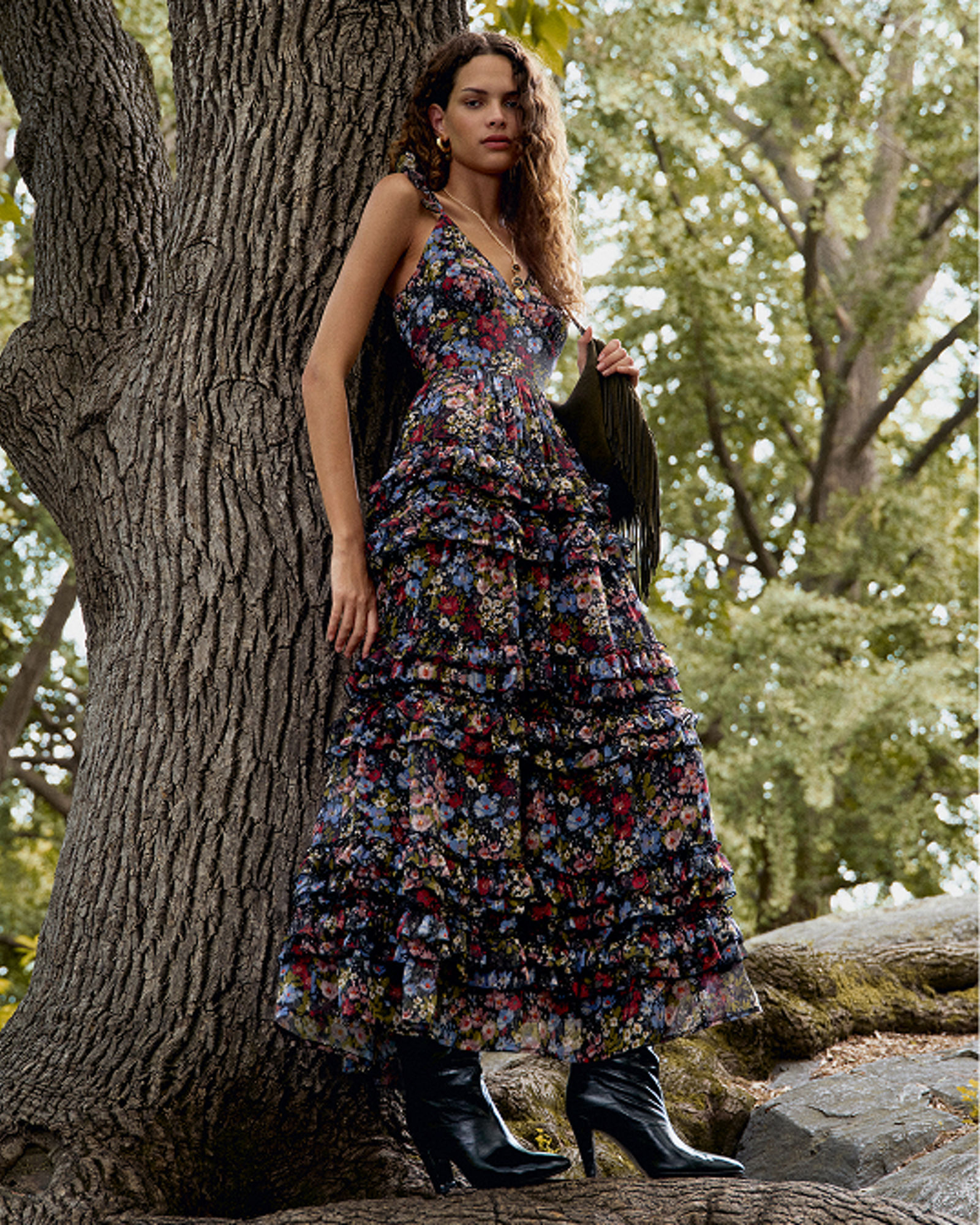 A woman leaning against a tree in a dark boho style maxi dress. Get ready for fall. Shop fall dresses.