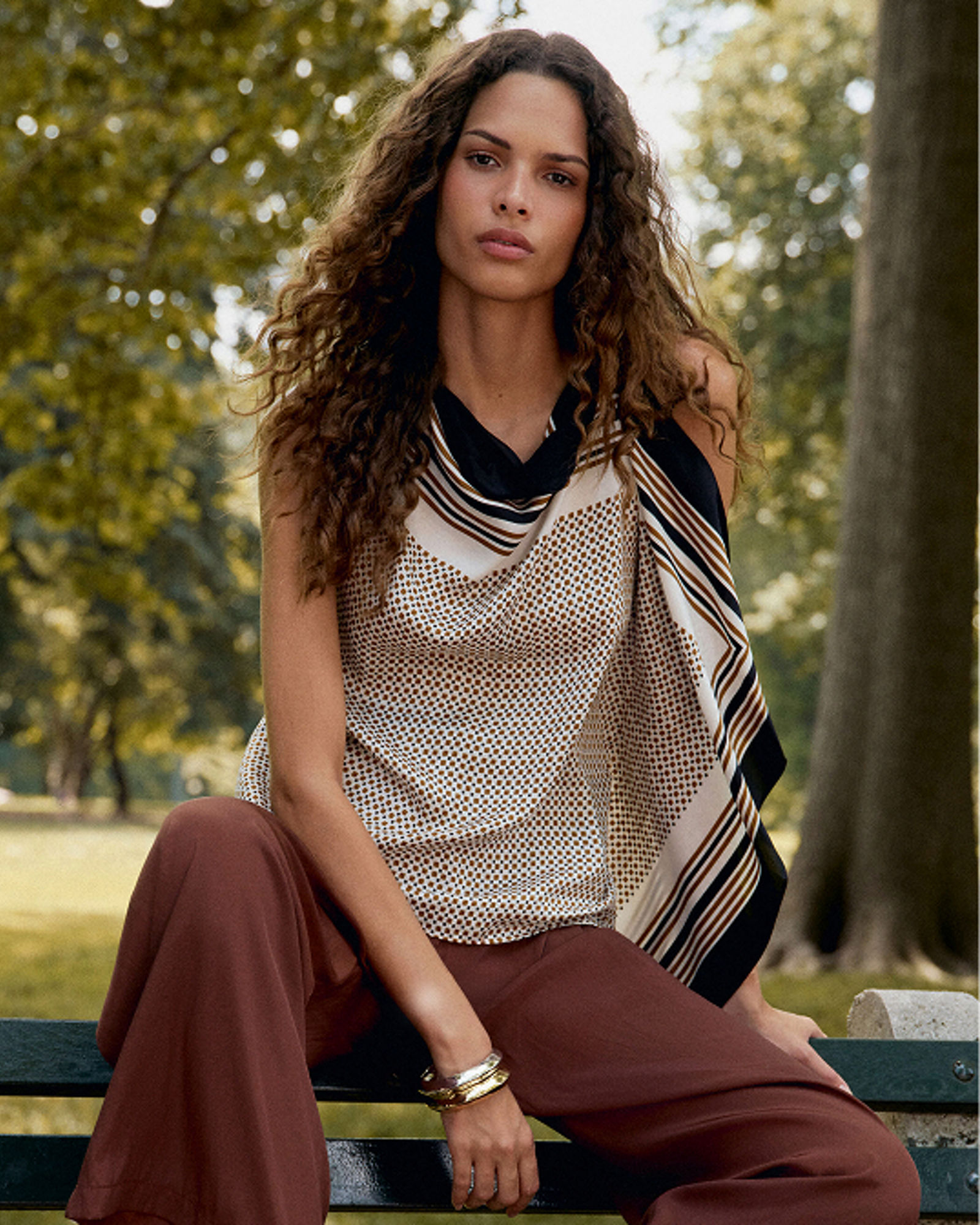 A woman in a bandana style top and brown pants. Get ready for fall. Shop tops.