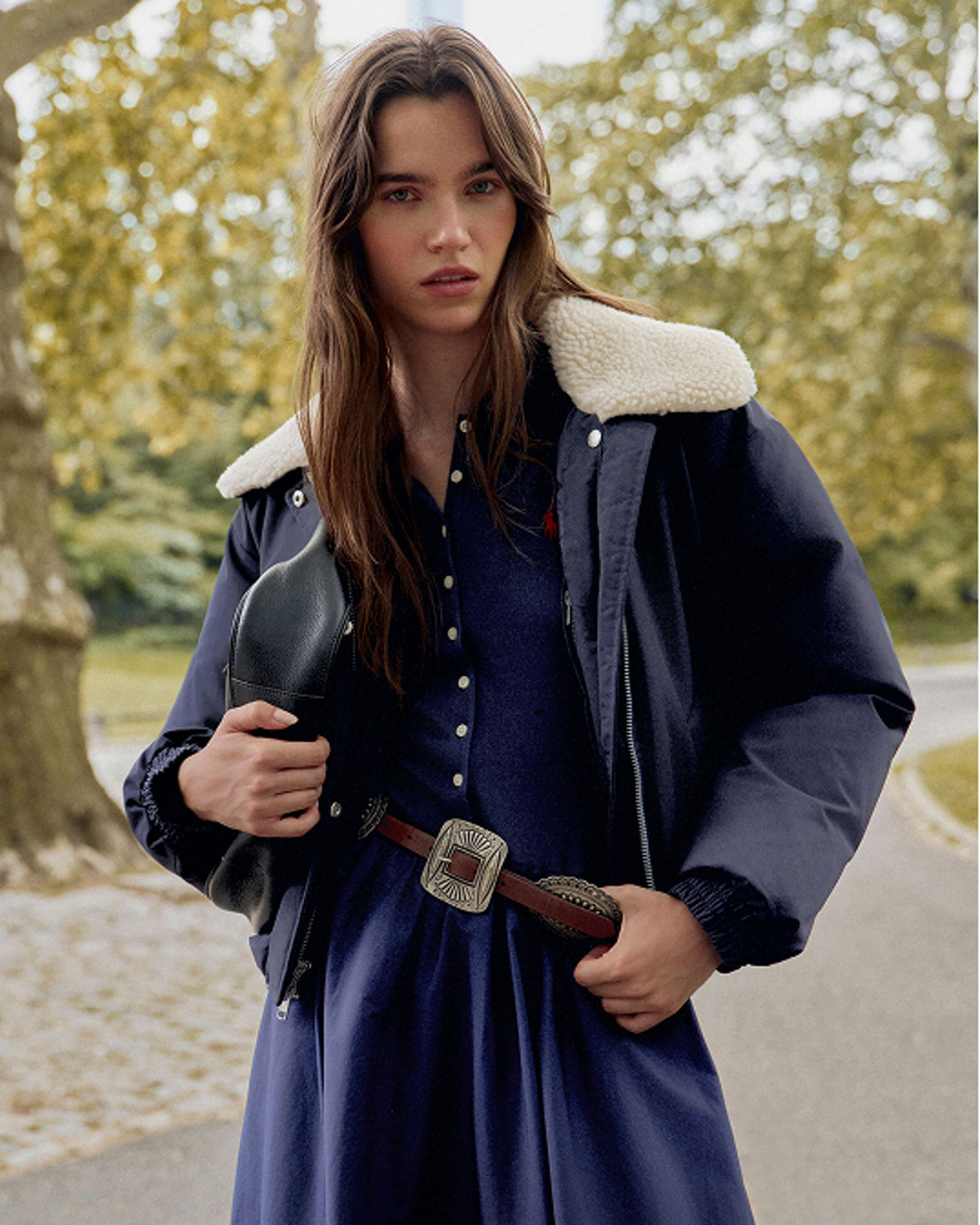 A woman in a dark blue jacket with shearling collar and blue dress. Get ready for fall. Shop womens jackets.