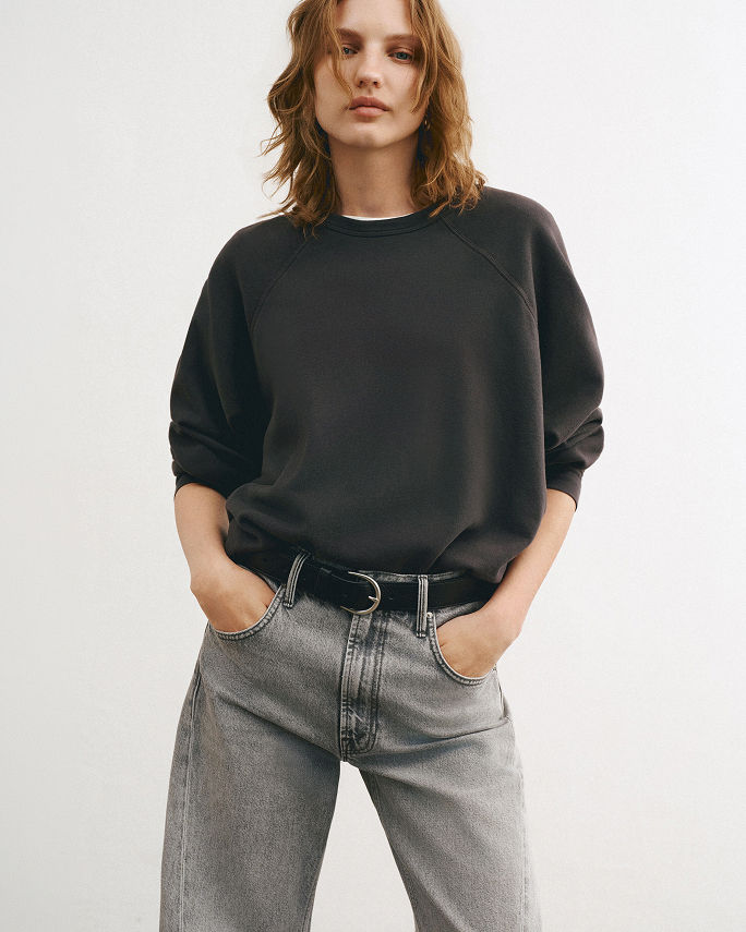 A woman in gray Mother jeans & black sweatshirt. Denim labels we love, Mother.